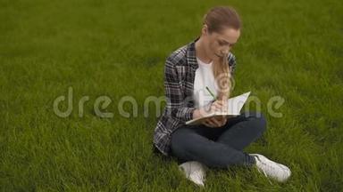 少女坐在草地上，在<strong>笔记</strong>本上做<strong>笔记</strong>。 十几岁的女孩坐在草地上，在<strong>笔记</strong>本上记<strong>笔记</strong>。 4K